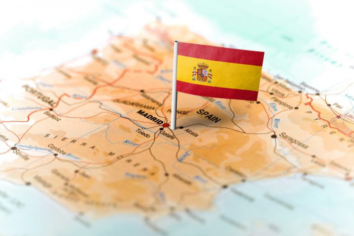 Spain flag srtanding on a map of Spain.